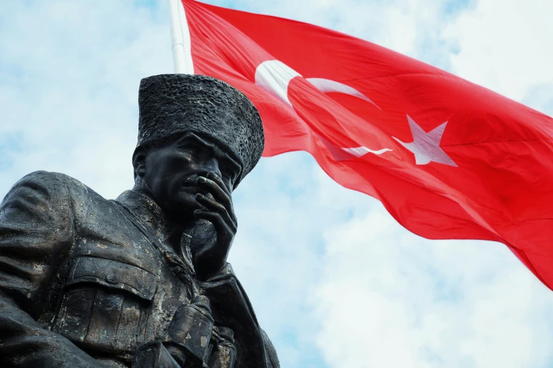 a statue of the turkish dictator, with his flag flying above it