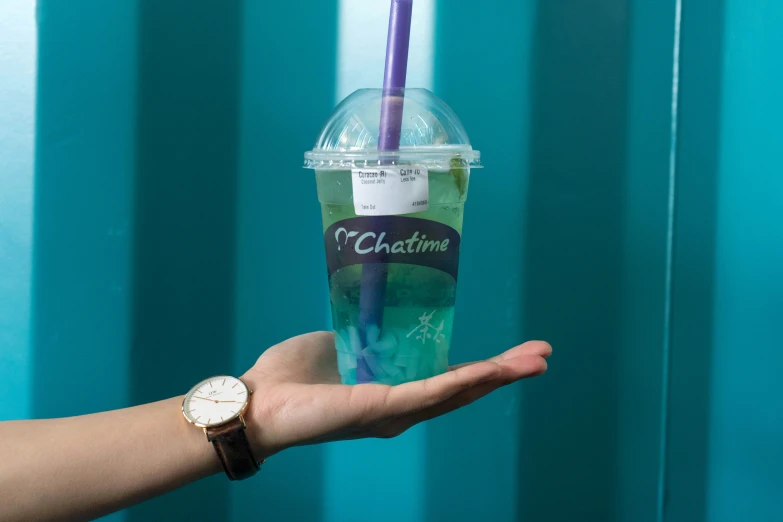 a hand holding up an iced drink in a cup