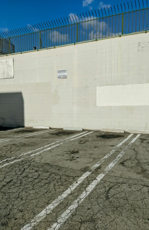 a empty parking lot with a wall painted white and fenced in