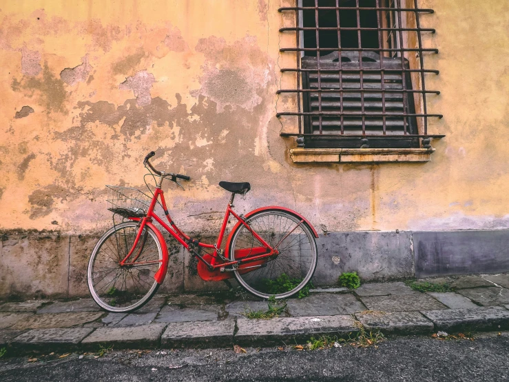 a red bicycle parked next to a building and window