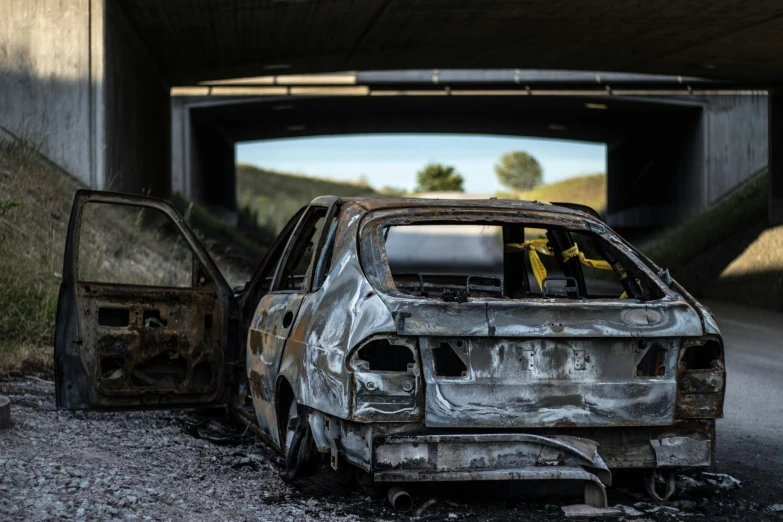 burned out car parked on side of highway near underpass