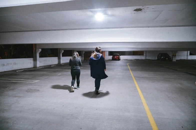 people walking in an empty parking garage at night