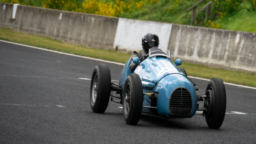 an old blue race car is going around the track