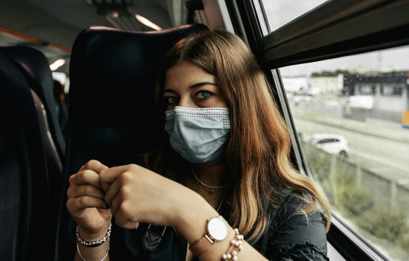 a woman with a medical mask on sits in a train