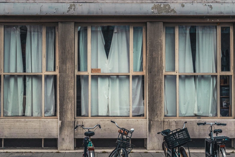 two bicycles parked on the street near tall windows