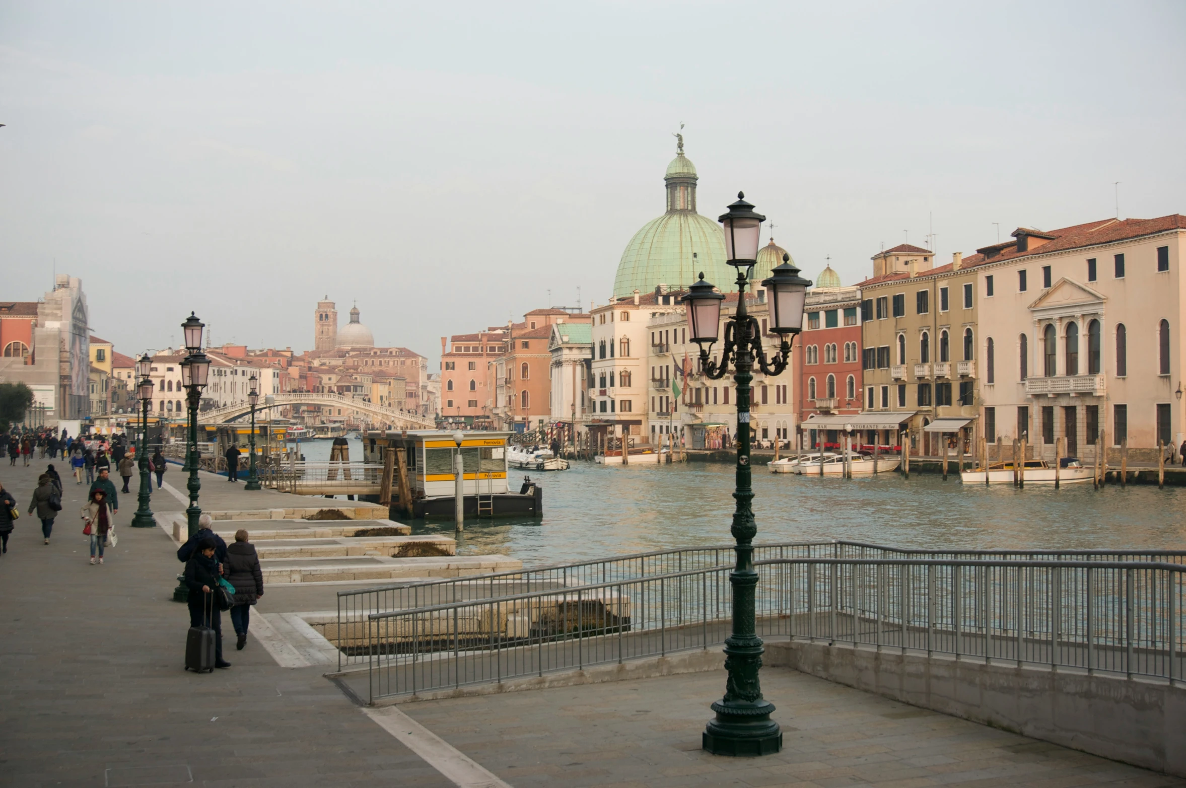 people walking along a path in a city by the water