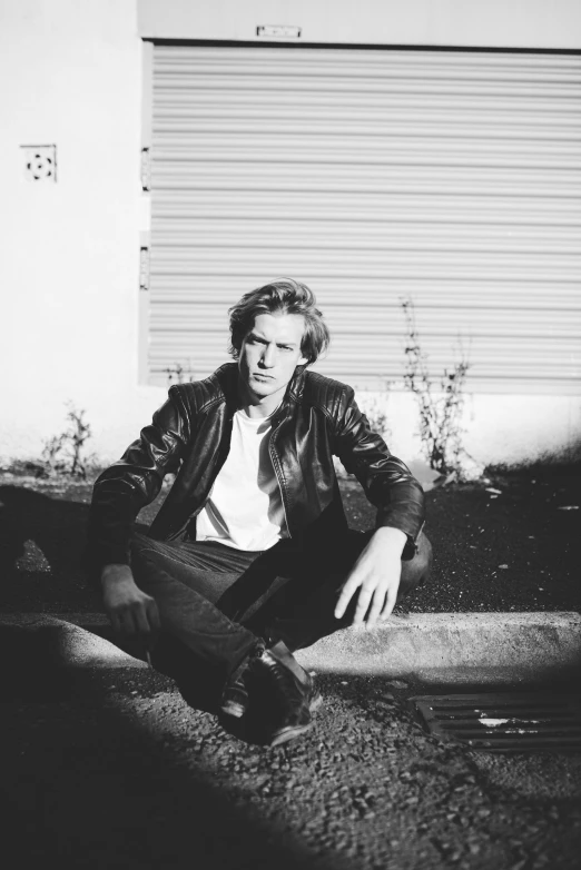 black and white po of a man sitting on the ground with his skateboard