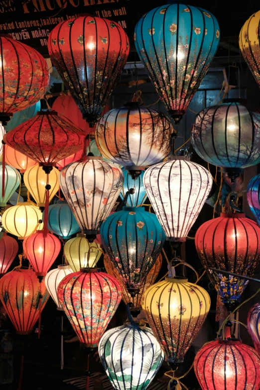 dozens of lit lanterns are displayed on a table