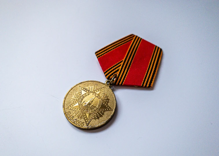 a red and gold tie and a small medal on a white table