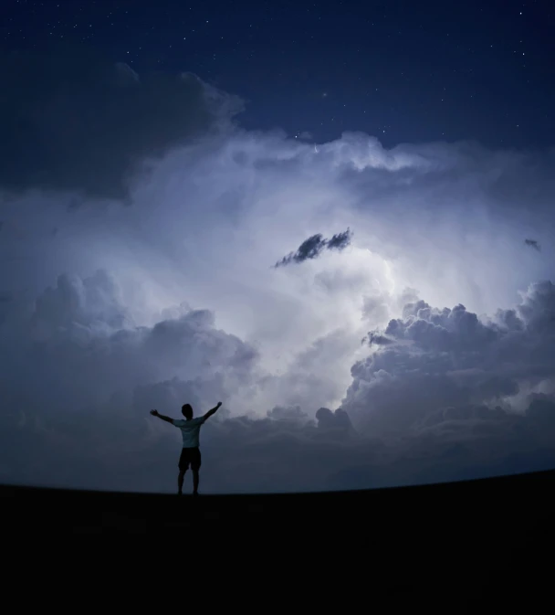 a man on a hill with his arms in the air