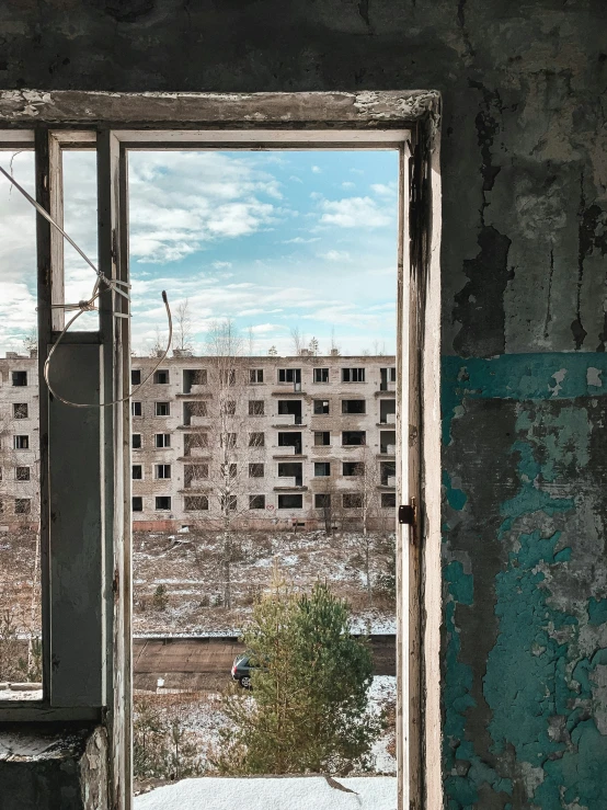 an open window in a run down building shows a snow covered yard