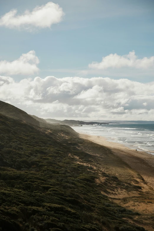 a train sitting next to the beach under some cloudy skies