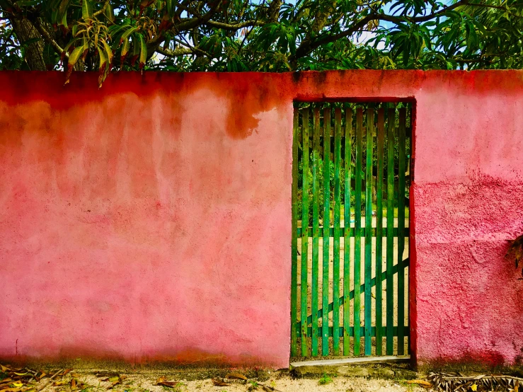 a pink wall and a green doorway with a small fence