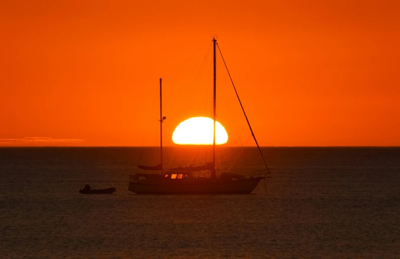 a boat is floating at sunset by the ocean