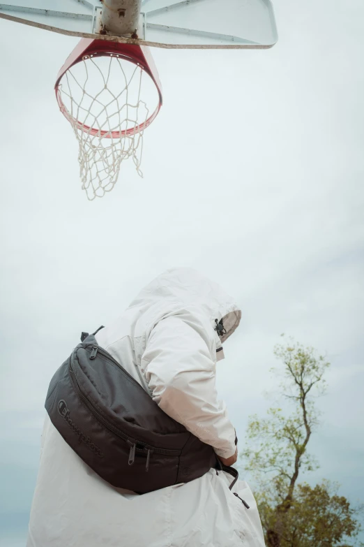 a man with a back pack on standing near a basketball hoop