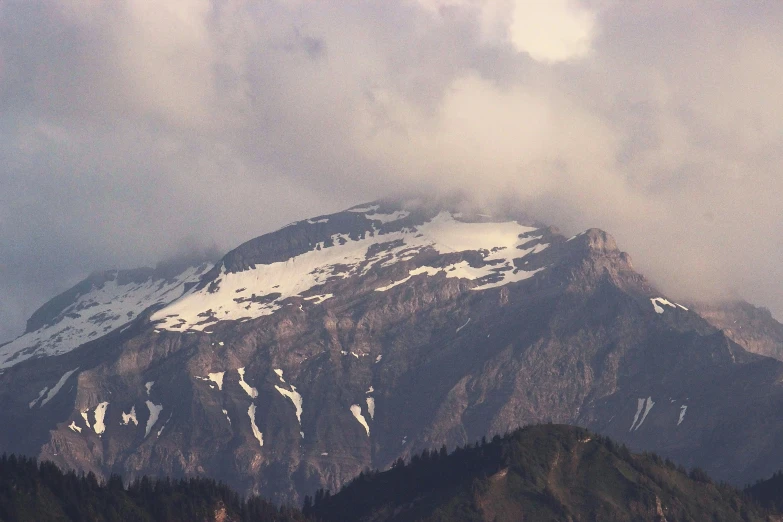 a snow capped mountain with many layers of clouds on top of it