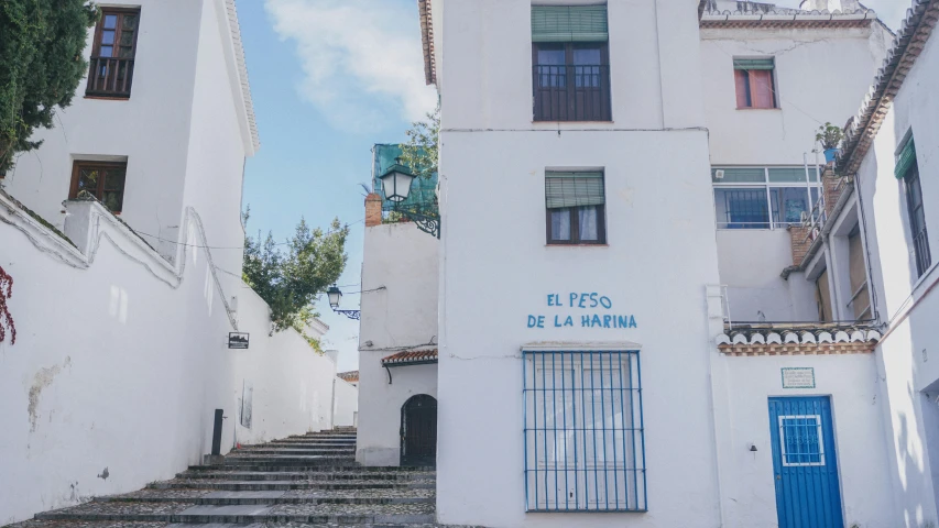 a white building with blue shutters and two floors