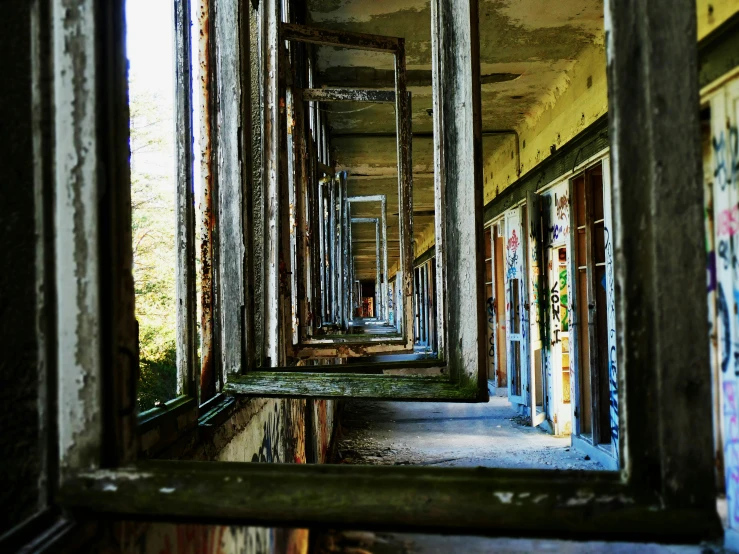 a corridor with graffiti, windows and poles