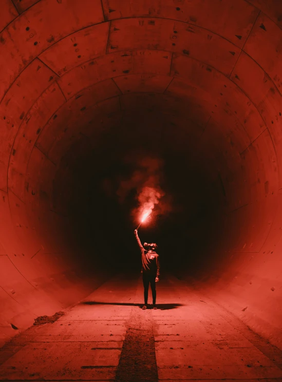 a person standing in a dark tunnel with their hand up