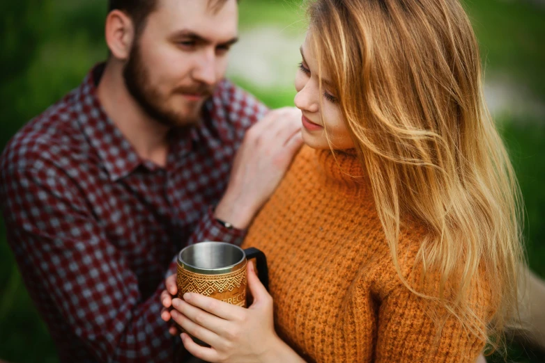 the man and woman are smiling together while they hold a coffee mug