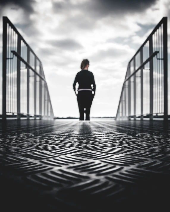 a woman walking over a bridge in the dark