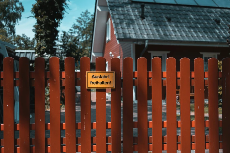 an orange fence with sign on it and a red house behind it