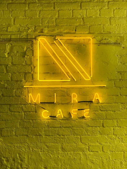 a yellow neon sign on a brick wall