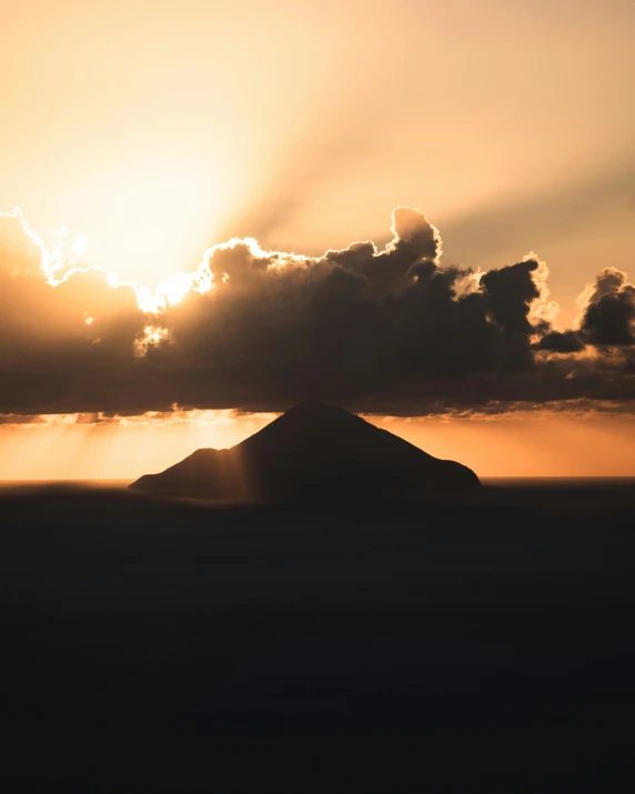 a volcano in the middle of the ocean under an overcast sky