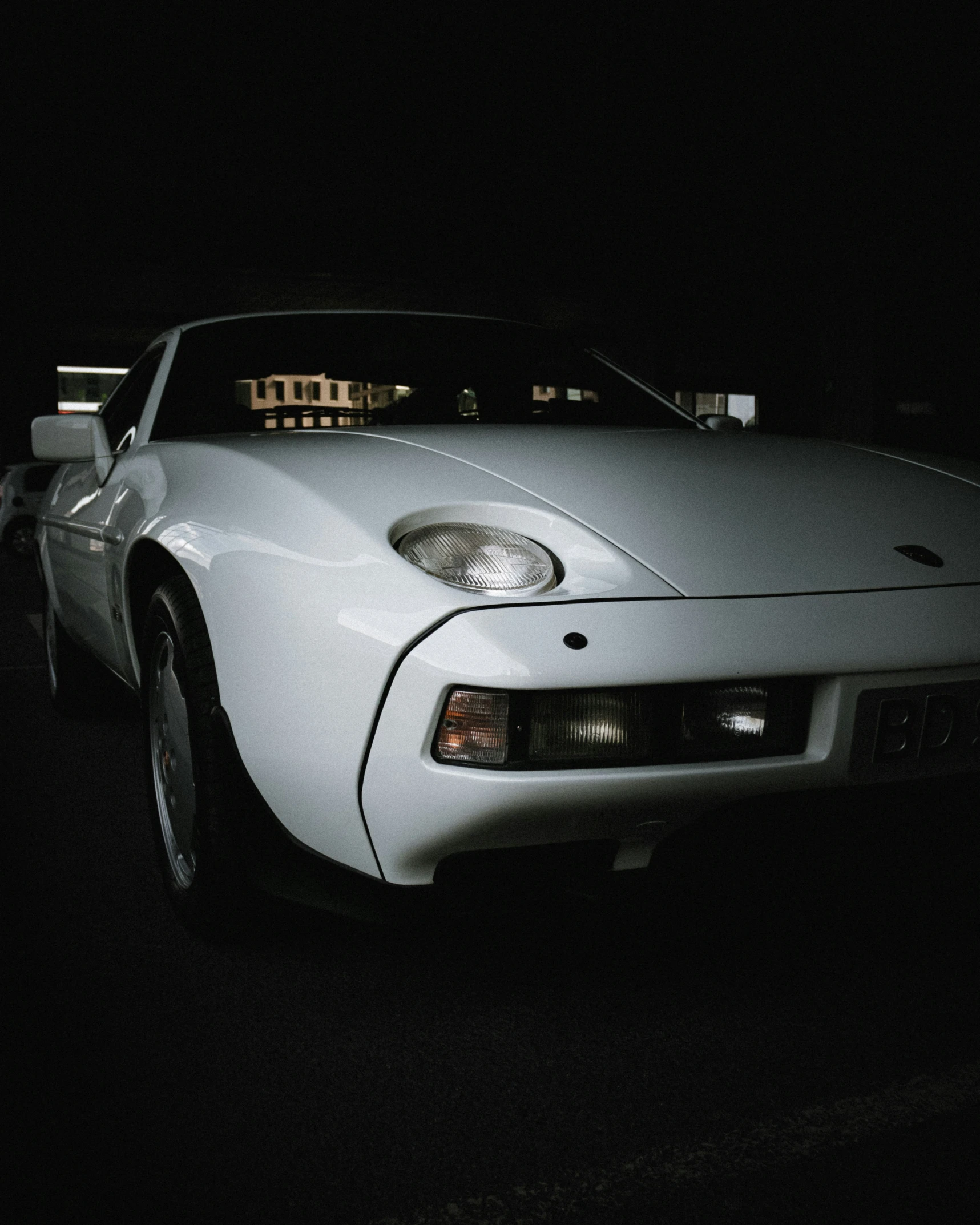 white sports car parked on the side of the road at night