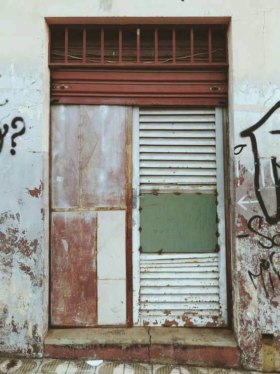 an old dirty building with doors and graffiti on it