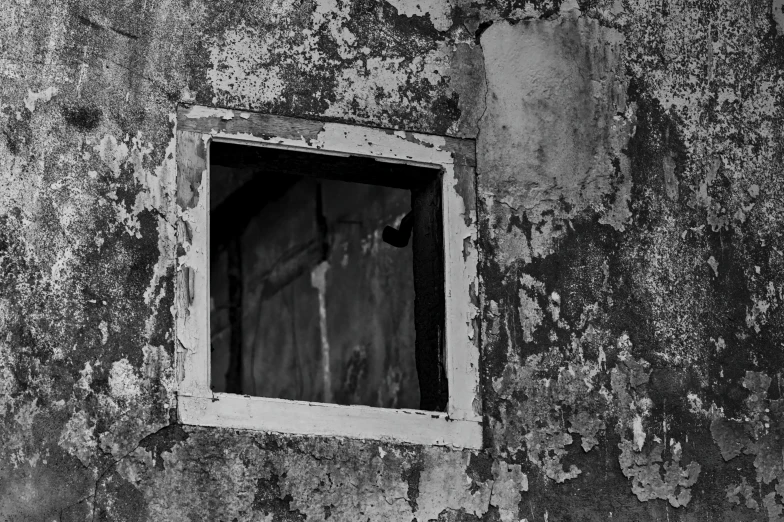 an old window with a peeling paint wall in black and white