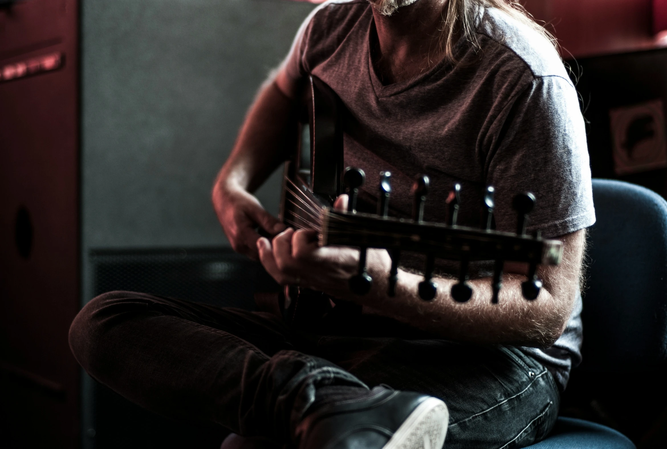 a male in a brown shirt playing an electric guitar