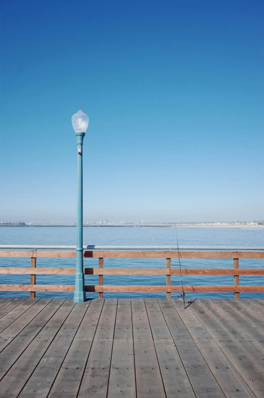 a street light on a wooden dock next to a blue sky