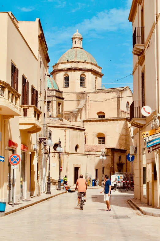 two people riding bicycles down an old fashioned street