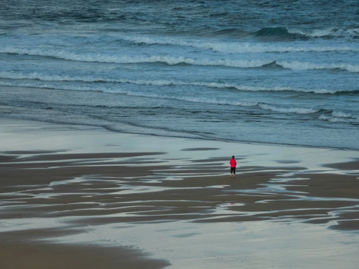 person on sandy beach with ocean waves in background