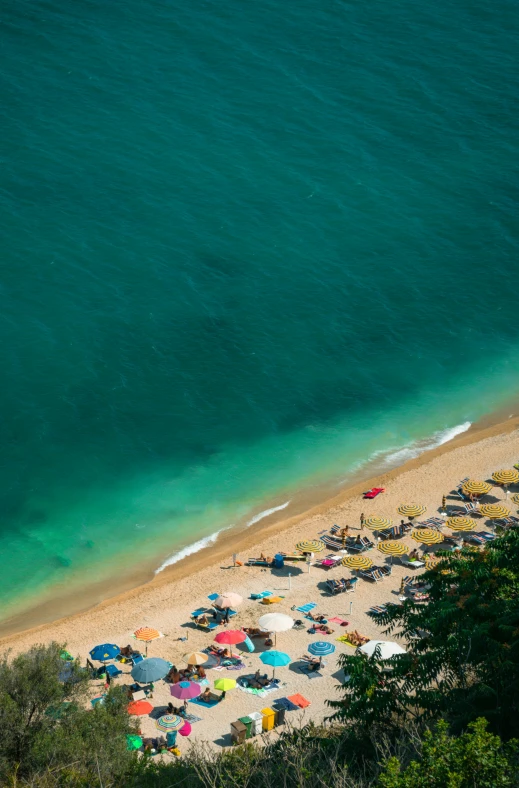 an aerial view of people relaxing on the beach with a bunch of umbrellas