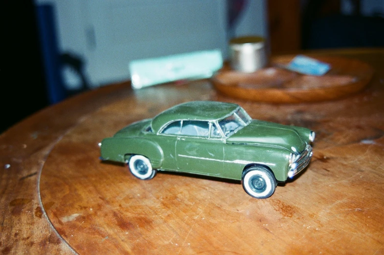 an antique model car on top of a wooden table