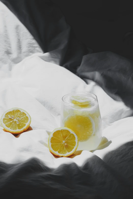 a pitcher and two slices of lemon on white linen