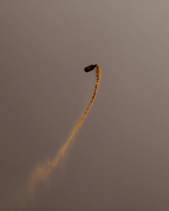 an orange stunt in the sky with some smoke behind it