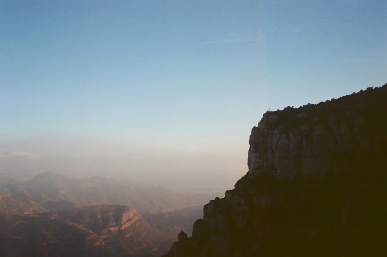 a bird flying over a mountain side next to the sky