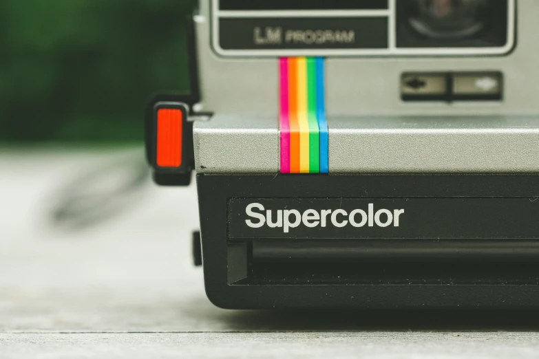 a silver camera with a rainbow stripe on it