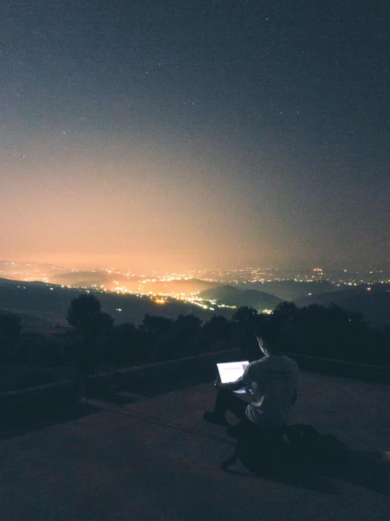 a person sitting at a bench using a laptop computer