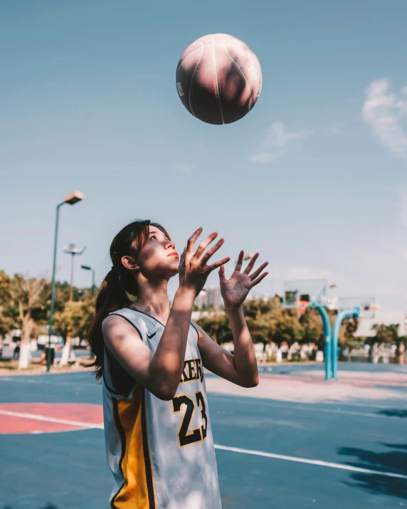 woman in grey and yellow uniform shooting a basketball