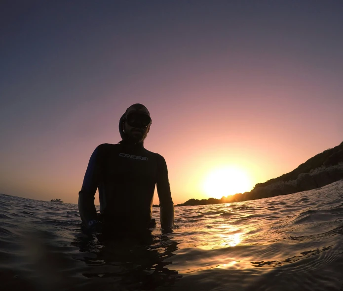 man riding on a surfboard with the sun in the background