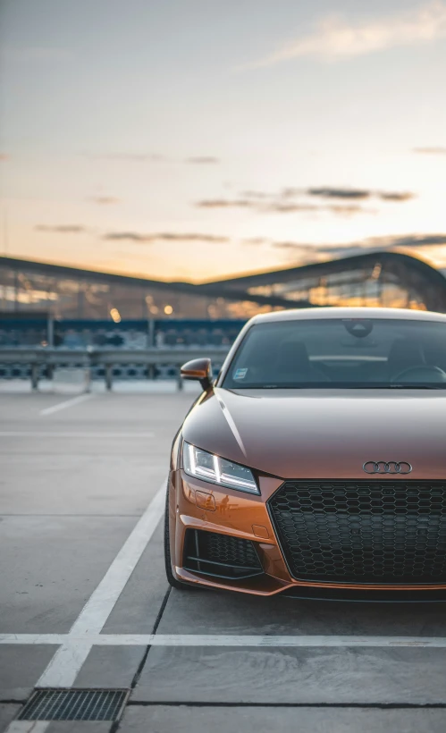 an orange sports car sits in a parking lot