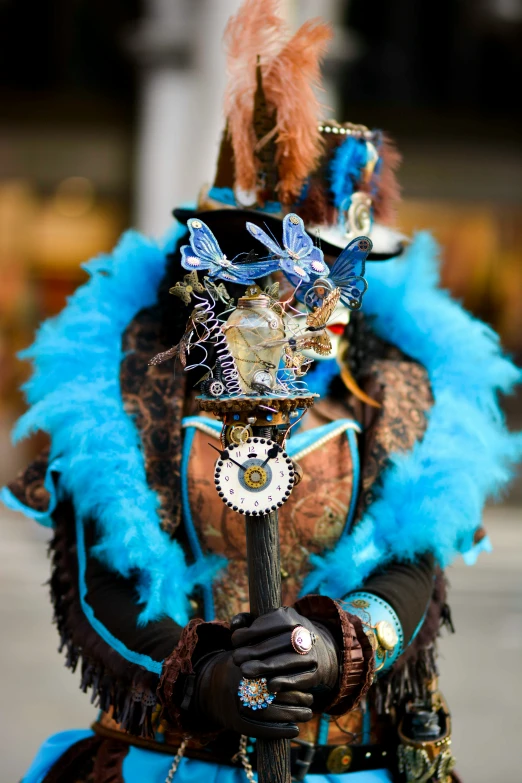 an ornate person wearing feathers holding a stick