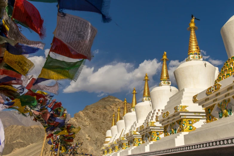 a row of white, yellow and blue buildings with a mountain behind it