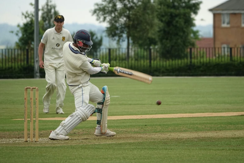 there is a male cricket player swinging the bat