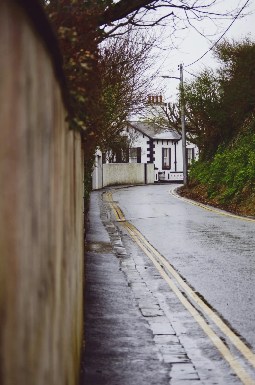 wet street with houses, trees and hills near by