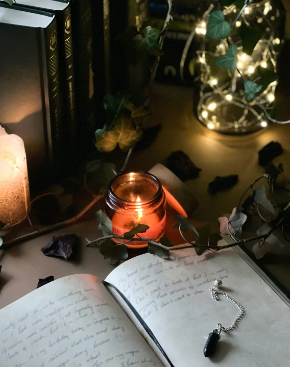 an open book with candles and a pen on top